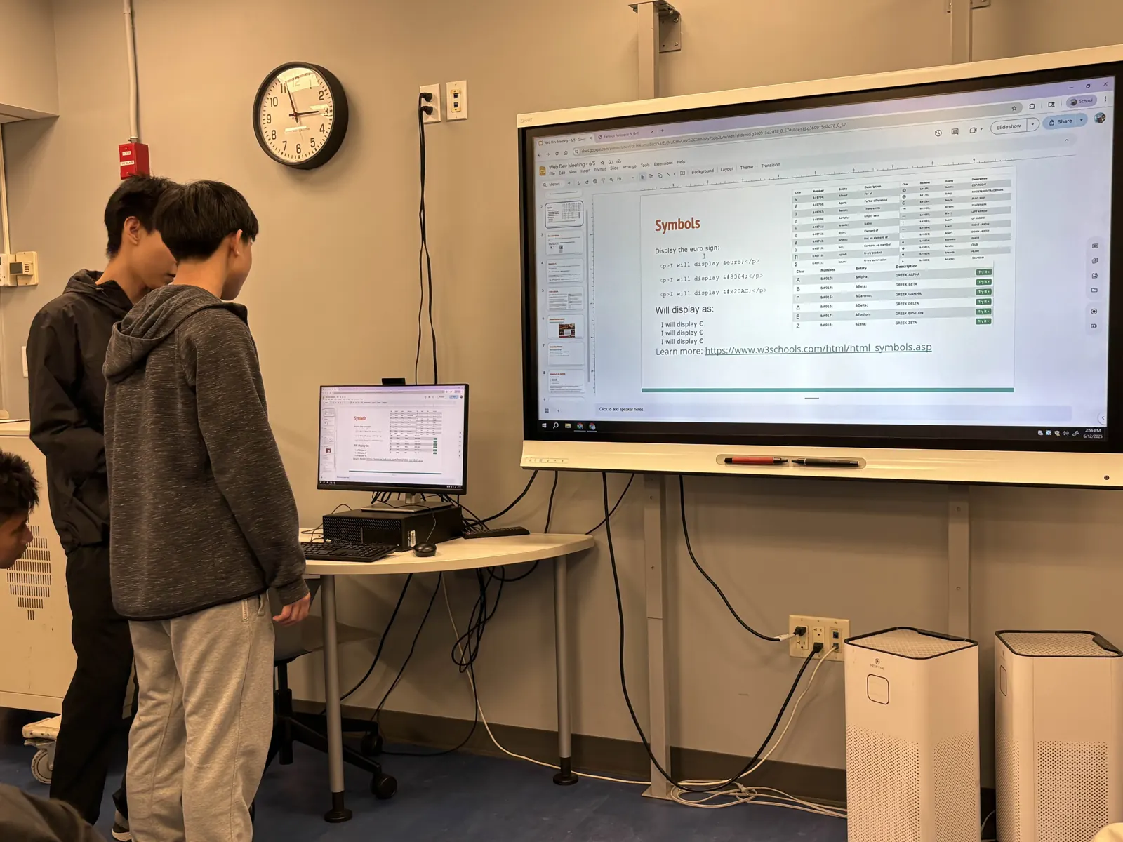 Two members walking through a coding exercise shown on the big screen